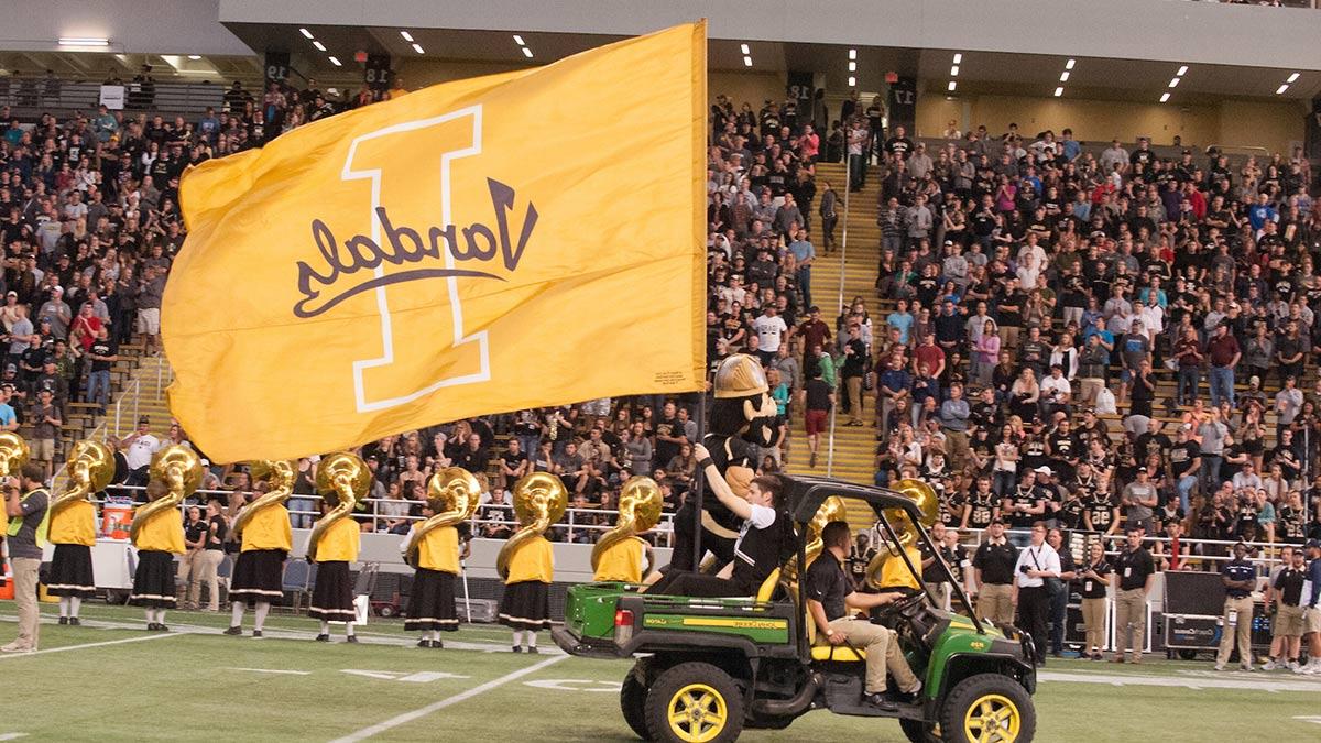 A tractor with Joe Vandal and a giant U of I flag drive through the Kibbie Dome